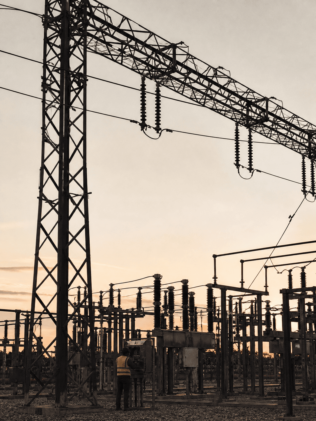 A field technician inspecting an electrical substation at dusk